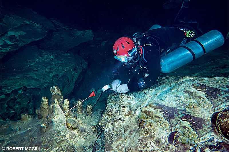 man diving in cave using a reel