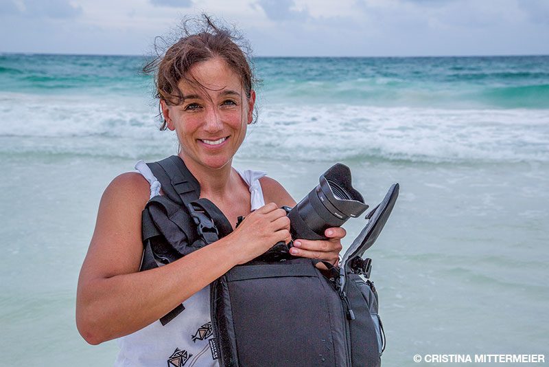 Cristina Mittermeier on the beach with her camera gear