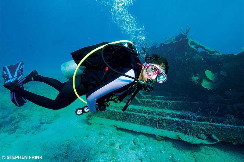 A female diver swims by an underwater shipwreck.