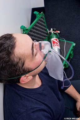 A nonrebreather mask is demonstrated to show proper use and oxygen flow.