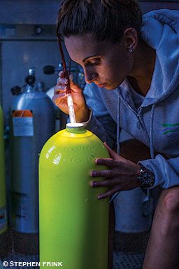 Woman uses a light to visually inspect a cylinder.