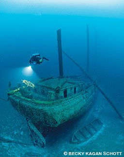 A technical diver illuminates the wheel on the stern of the Cornelia B. Windiate shipwreck.