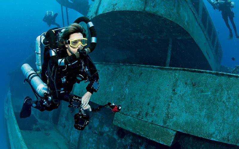 A diver swims next to a shipwreck