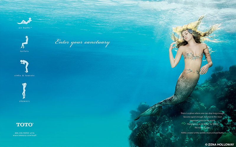 A mermaid basks on rock underwater