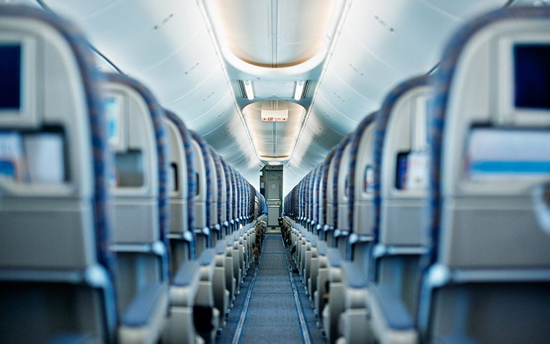 Straight down the center aisle of an airplane are empty seats