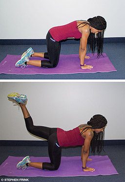 A personal trainer starts in table-top pose and is kicking her left leg back
