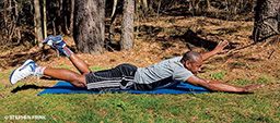 Male, Black, personal trainer lies on belly and wiggles his arms and legs