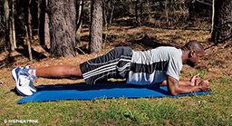 A male, Black personal trainer performs a forearm plank