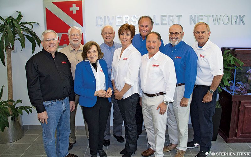 Seven men and two women pose in DAN headquarters. They are the DAN Board of Directors.