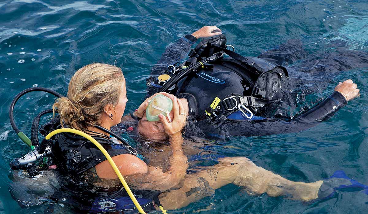 Female diver helps another diver in the water