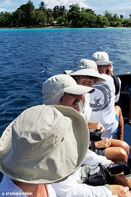 Four nerdy-looking boat passengers wear floppy hats