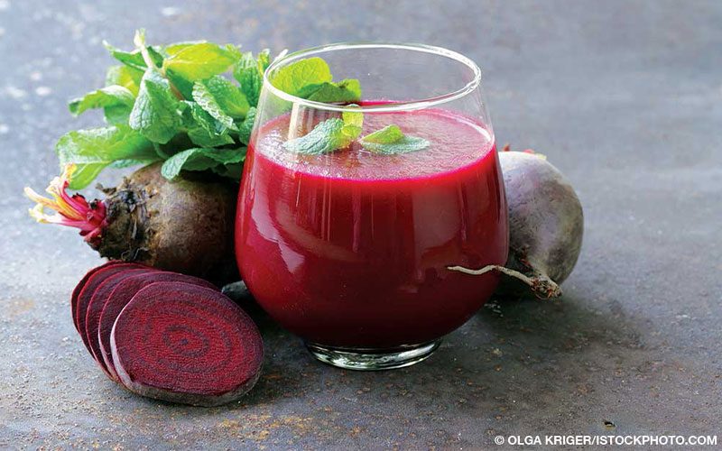 Glass of beet juice surrounded by beets