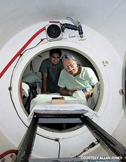 Man and nurse smile outside of a hyperbaric chamber