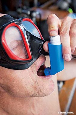 Man in goggles uses a blue inhaler