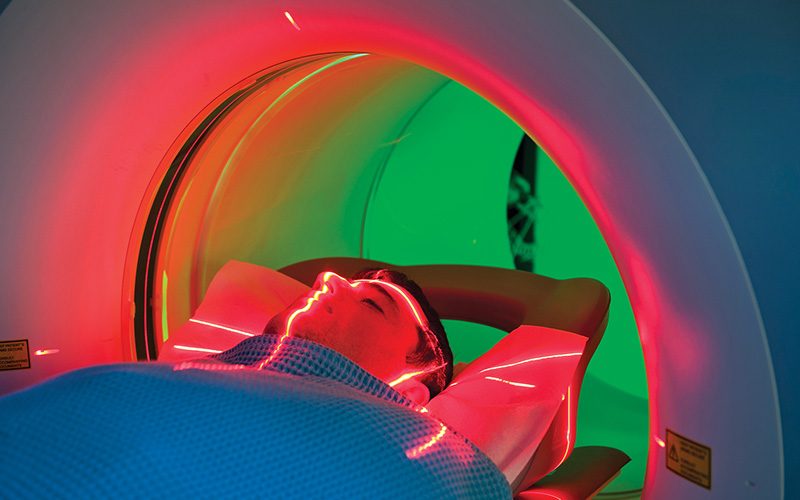 Man receives a CT scan and red laser is around head