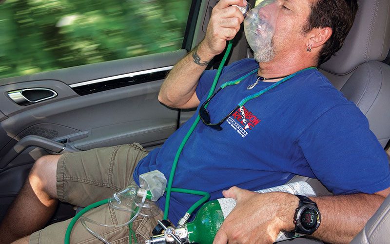 Man sits in a car wearing oxygen mask