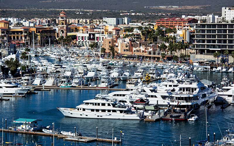 A marina at Cabo San Lucas with boats in the water and hotels surrounding the water