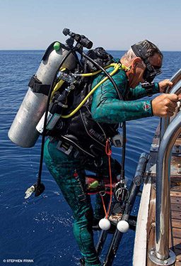 Old man diver climbs up ladder wearing all gear