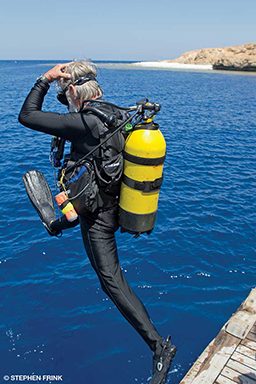 Old man scuba diver jumps into water