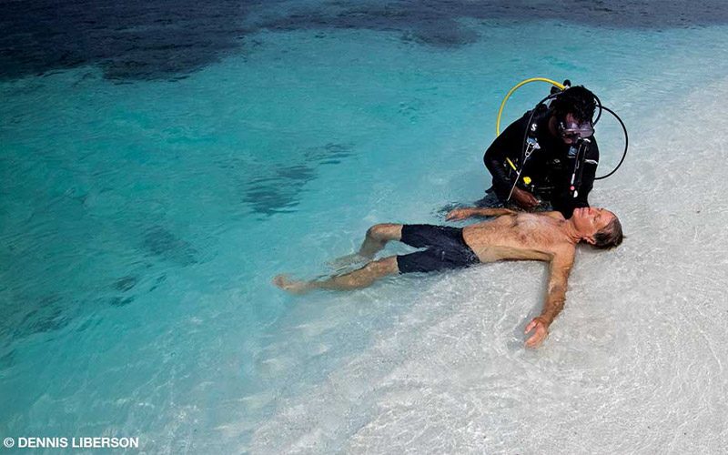 Unconscious man on beach gets help from a scuba diver