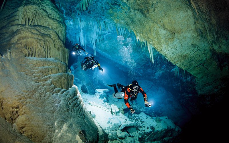 Three tech divers explore a dark cave
