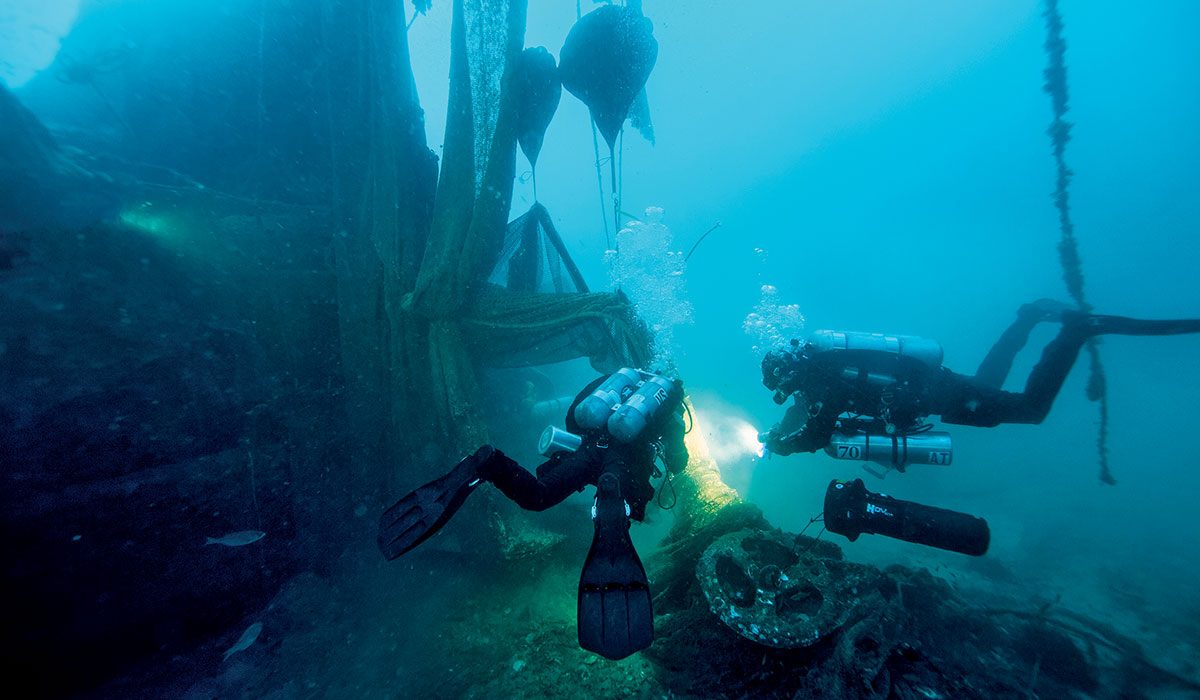 Two divers approach shipwreck and cast-off nets