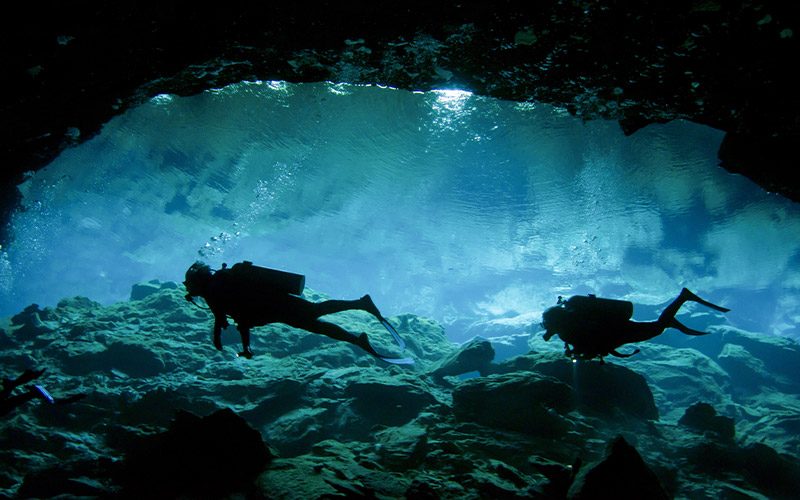 Two divers float in cave
