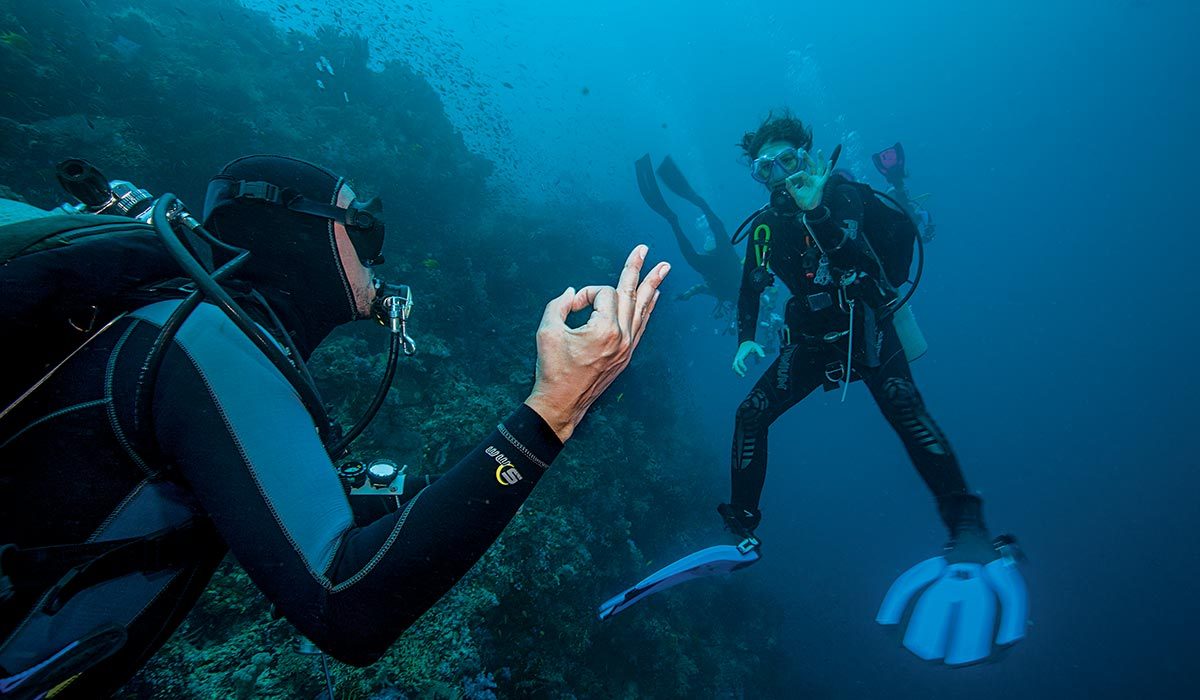 Two divers give the OK symbol to each other