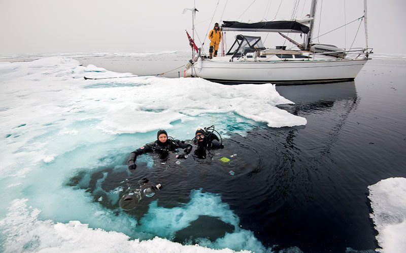 Two drysuit divers tread water near ice cap