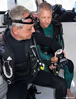 Two male divers look at a computer after a dive