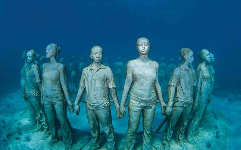 A circle of underwater people statues holding hands
