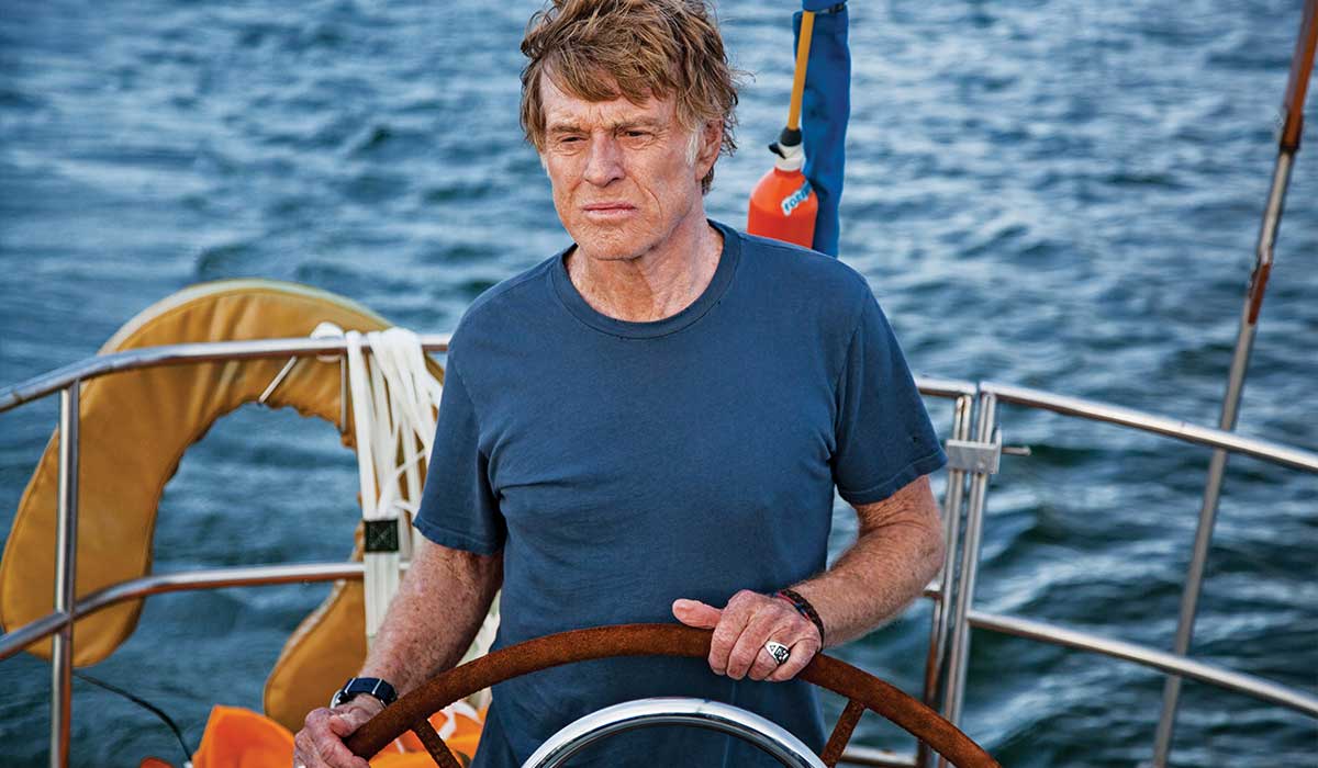 Actor Robert Redford behind the helm of a boat