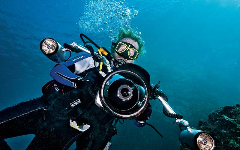 Bearded scuba diver holds a big underwater camera