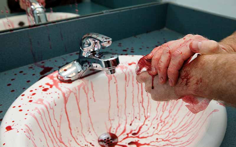 Bloodied hands over a blood-covered sink