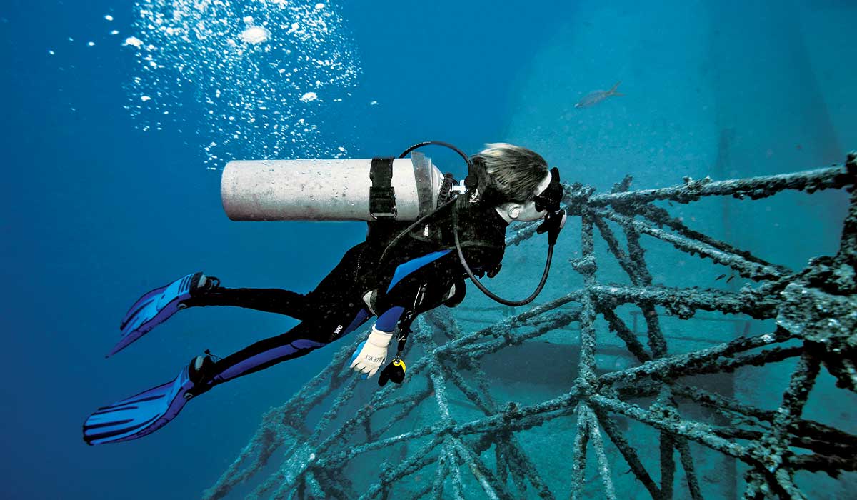 Child diver swims over a shipwreck