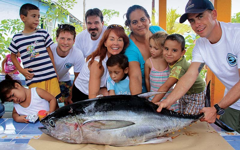 Children and adults pose together with a dead fish
