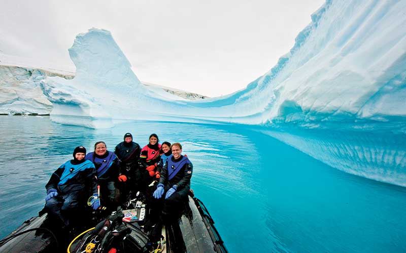 Dive crew poses on a boat with ice in the background