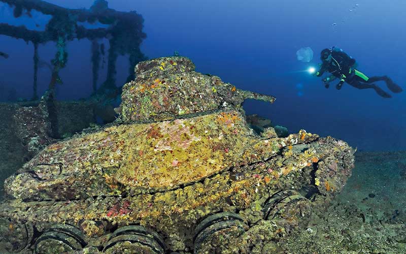 Diver approaches a sponge-encrusted sunken tank
