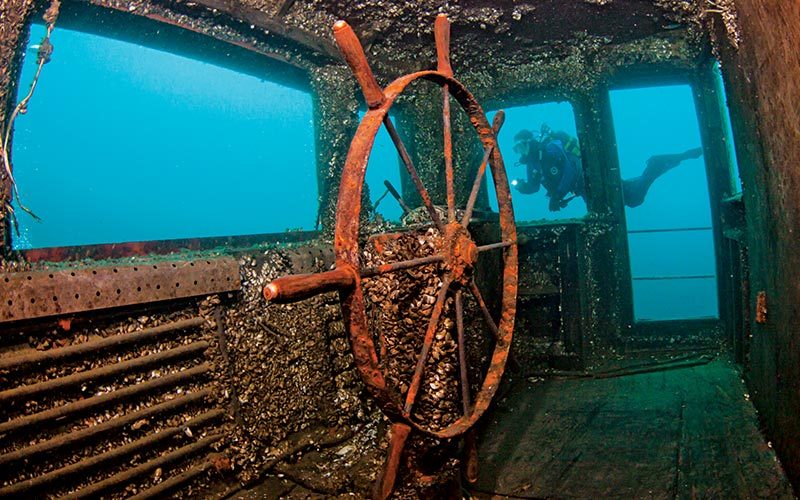 Diver explores the pilot house of a sunken ship