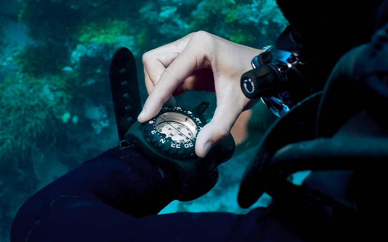 Diver fiddles with compass watch on left arm