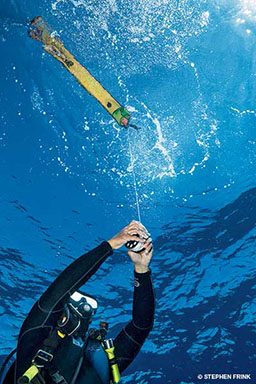 Diver holds onto line of yellow buoy marker