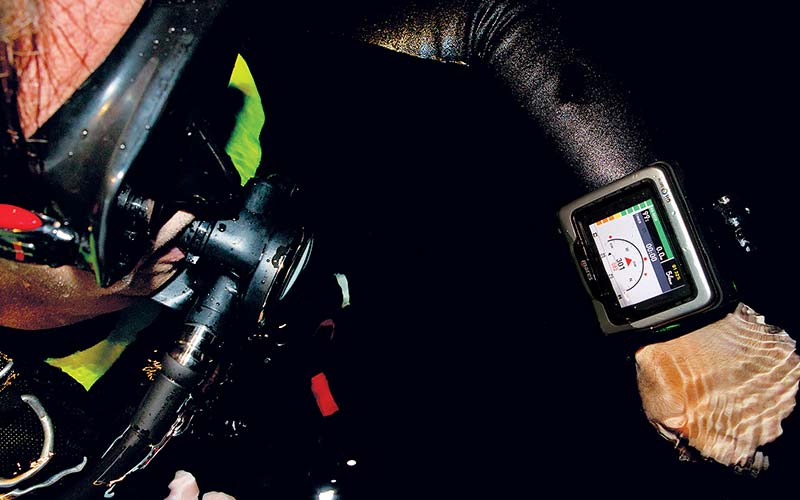 Diver peers at digital compass watch looped on left arm