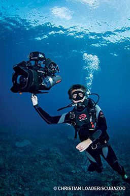 Diver shows off buoyant camera rig. They are balancing it on one finger.