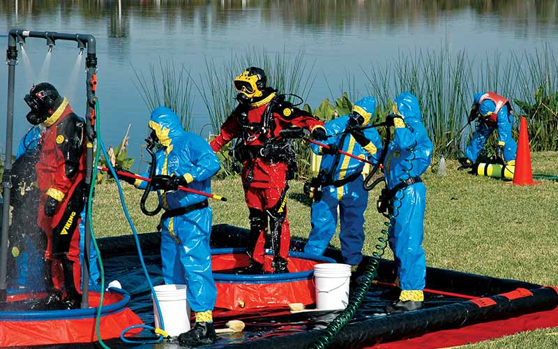 Divers in red suits get disinfected by people in blue suits