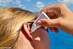 Ear drops from white bottle are administered into right ear