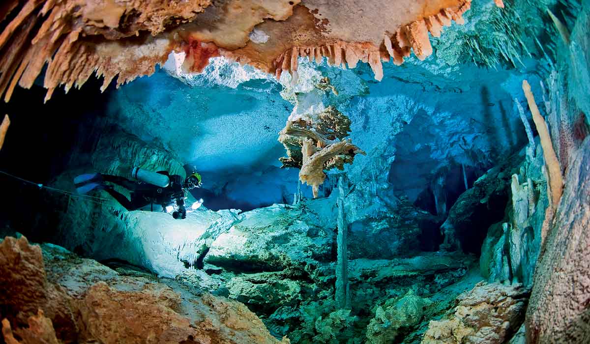 Female diver explores a dreary cave