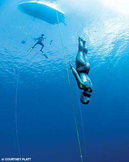 Female freediver swims down head first