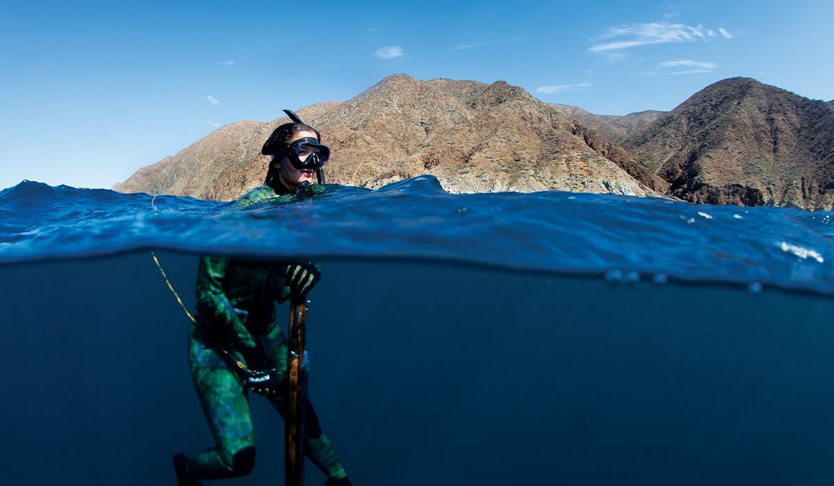 Female freediver takes a break while floating and holding her speargun