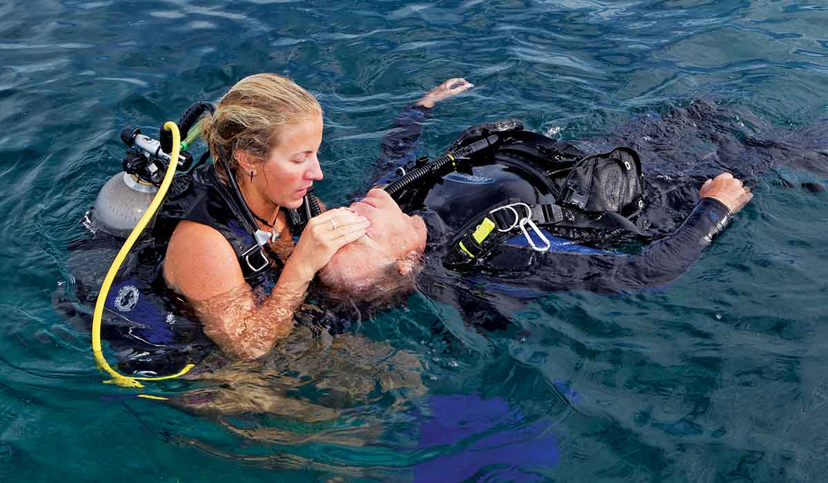 Female rescuer works with an unconscious diver in the water