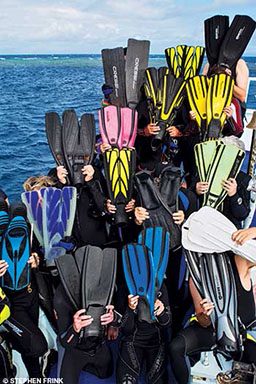 Group of divers hold up their fins to cover their faces